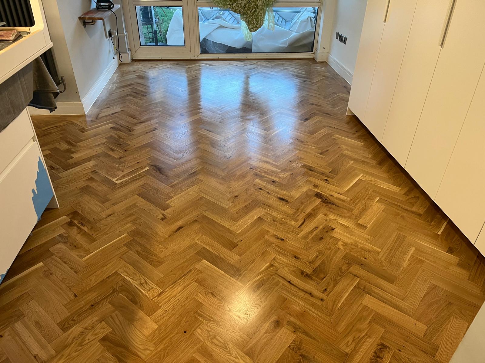 Parquet Floor Sanding in Harrow on a newly restored oak herringbone parquet wood floor in a bright modern room.