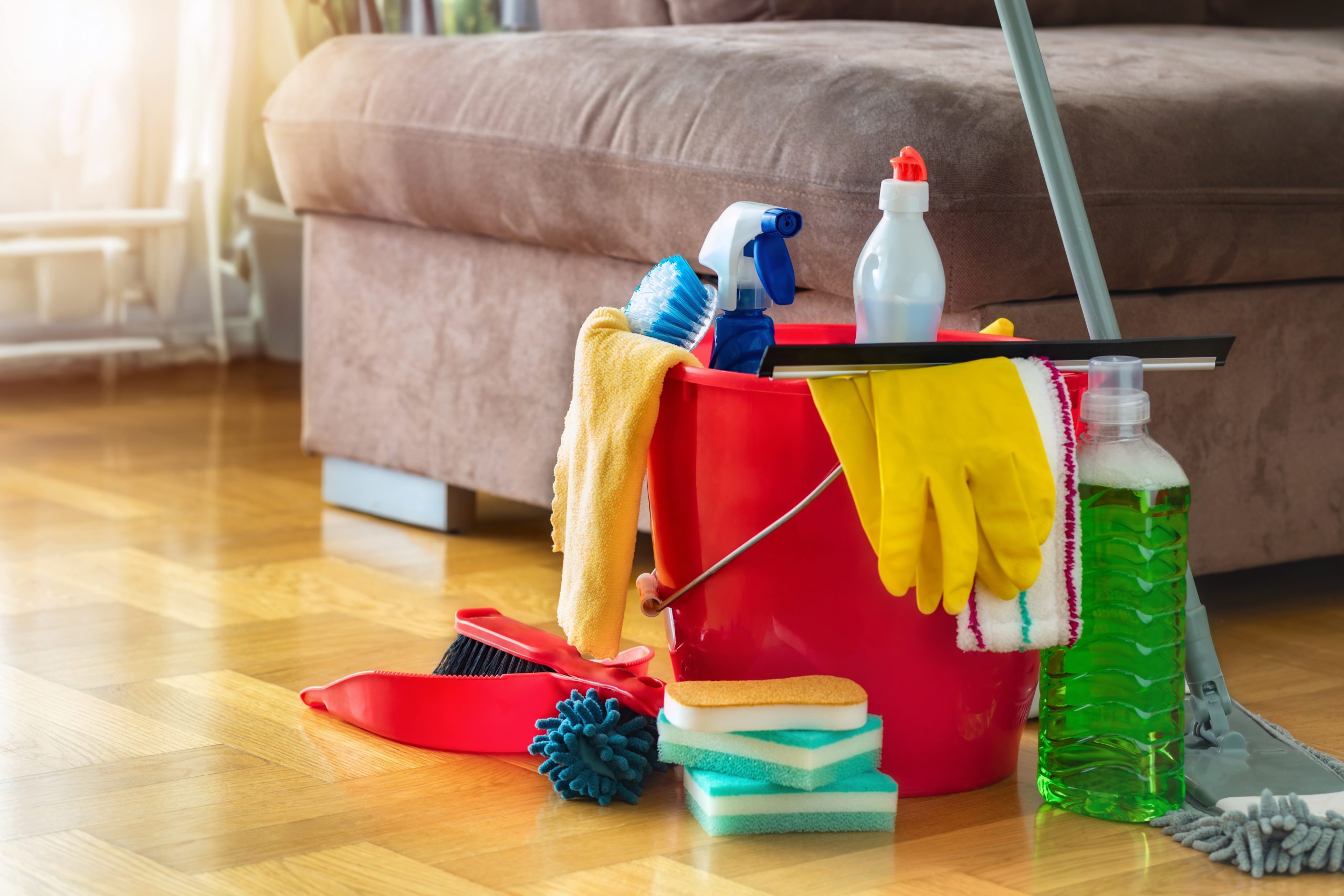 After Parquet Floor Sanding in Harrow, a light oak parquet wood floor in a living room with cleaning bucket, gloves and mop ready for gentle aftercare.