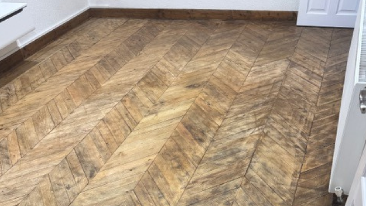 Parquet Floor Sanding in Harrow on a worn oak chevron parquet wood floor before restoration in a small room.