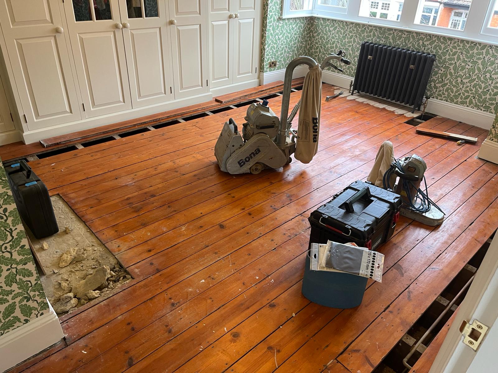 Wood Floor Sanding in Harrow on original pine floorboards, with sections lifted for repairs and professional Bona sanding machines set up in a bedroom.