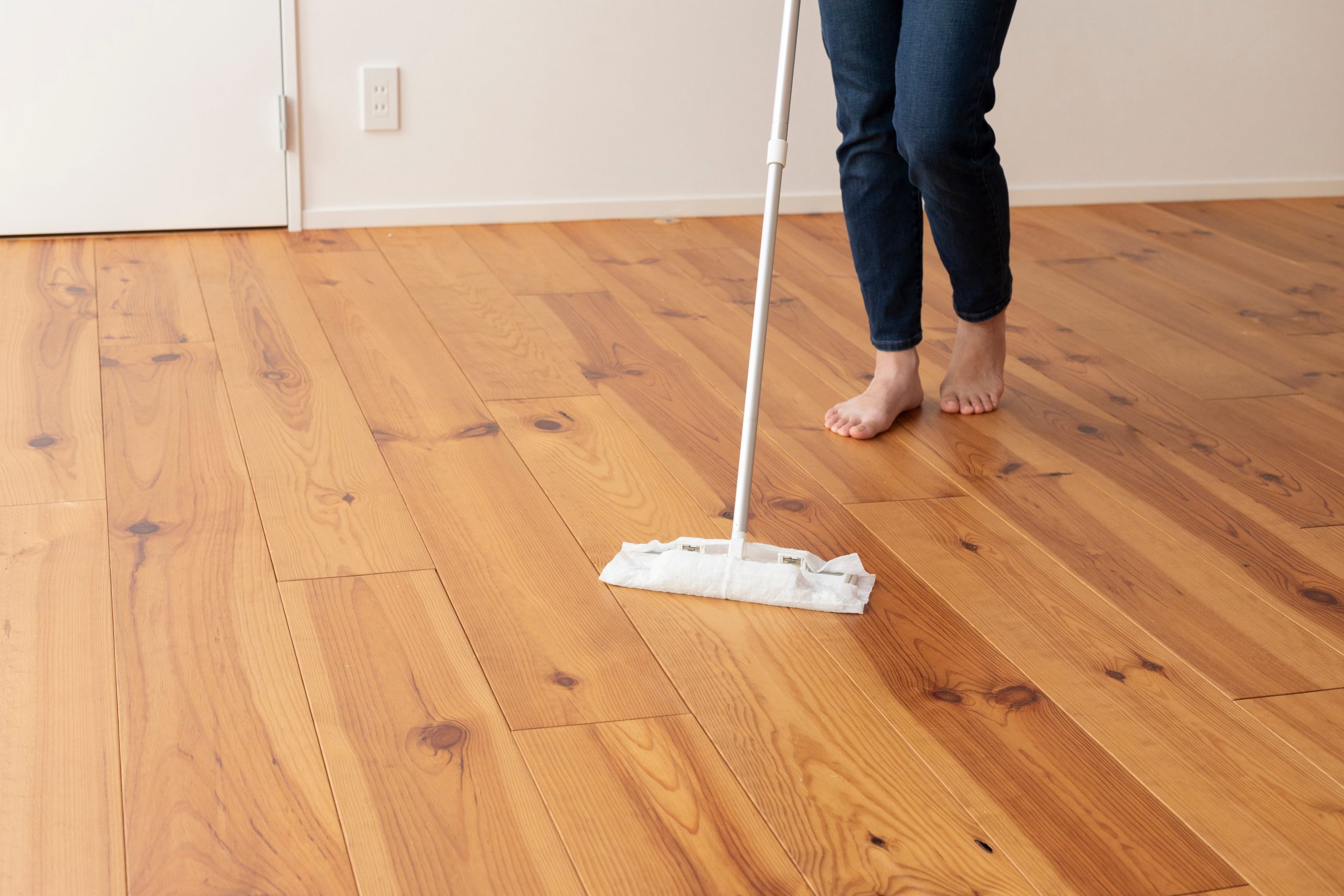 After Wood Floor Sanding in Harrow, a person gently cleaning solid pine floorboards to maintain the freshly restored hardwood surface.